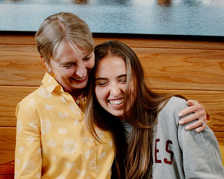 Two people sitting close together in a warmly lit room, leaning in toward each other.